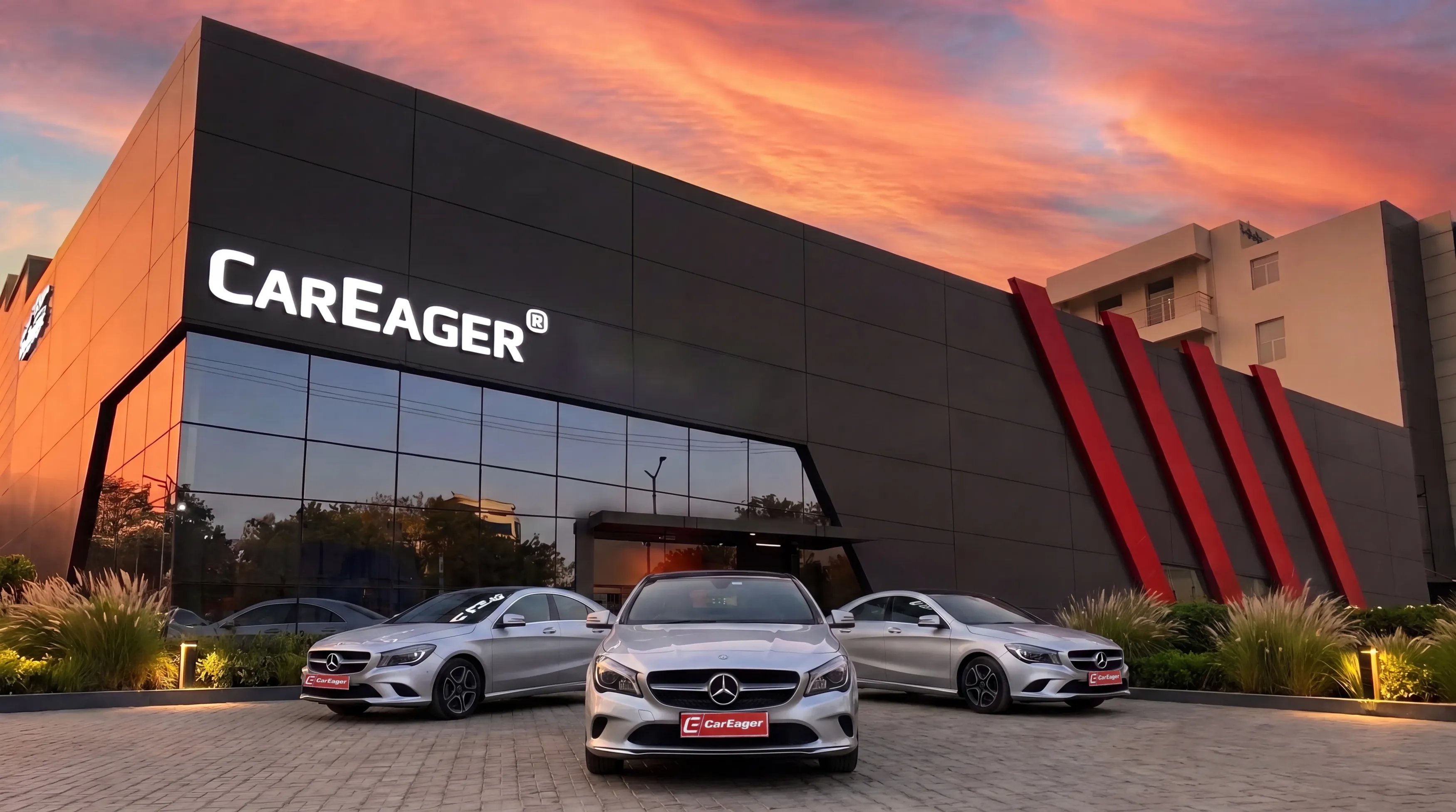The CarEager flagship at dusk — a black glass facility with an illuminated CarEager sign and three CarEager-plated Mercedes out front, Sector 35, Gurugram